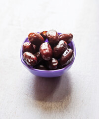 dates on purple bowl white wood background