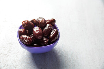 dates on purple bowl white wood background