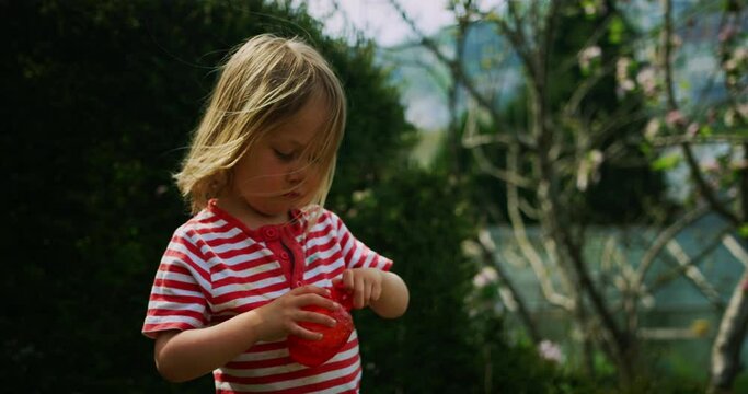 Little preschooler boy blowing bubbles in the garden