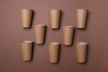 eight brown eco-friendly cardboard cupd lie on brown colored paper background in chessboard order