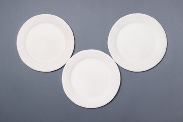 three eco-friendly white cardboard plates in form of mouse lie on gray background. Top view. Close-up