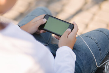 Young boy play online games on smartphone and using powerbank for charging. Handsome teenager use phone otside
