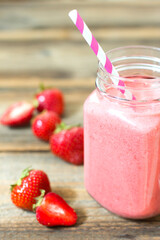 Fresh strawberry smoothie on wooden table.
