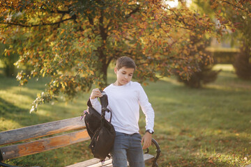 Naklejka na ściany i meble Schoolboy go to school in the morning. Happy teenager in white shirt with black backpack go to study