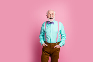Photo of funny aged grandpa good mood standing self-confident hands pockets open mouth wear mint shirt suspenders bow tie brown pants isolated pink pastel background