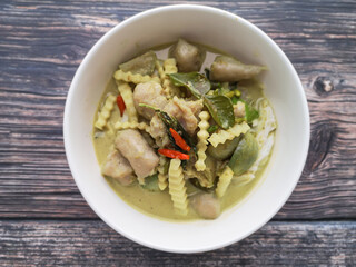 Green curry with fish ball and Coconut Shoots in white bowl on wooden background.Thai food call name 