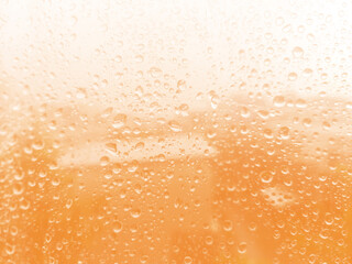 Close up rain drops on  plastic background.Water drops on window glass orange tone.