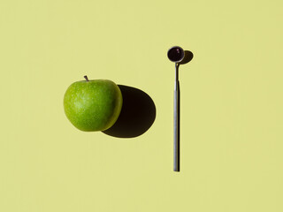 green apple and angled mirror on light olive background. horizontal. dental concept