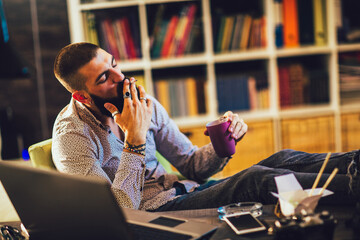 Young man sitting in office with a cup of coffee,smoking cigarrette