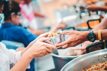 Hands of beggars accepting food from the hands of volunteers