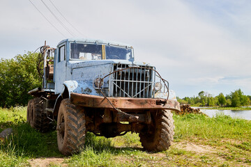 Fototapeta premium Dirty truck on a country green grass in a sunny summer day with blue sky.