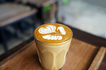 Close up glass cup of hot Latte art coffee on wooden tray table