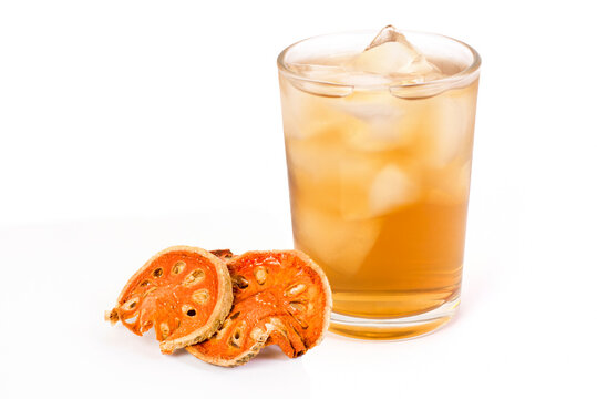 Glass cup of Bael fruit juice or quince ice tea and dried bael sliced fruit ( Aegle marmelos or wood golden apple ) isolated on white background. Herbal tea and healthy drinks concept.