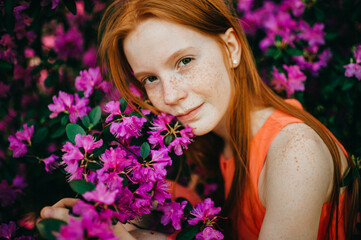 Fototapeta premium A cute girl in a summer dress enjoys plants in the botanical garden.