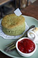 Close up Matcha green tea scone served with clotted curd cream and strawberry jam