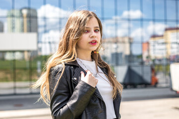 young blonde schoolgirl in black leather jacket posing in the parking lot