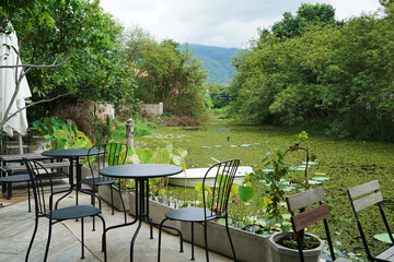 Outdoor dining space area of Restaurant terrace and coffee cafe with natural green lake view and cloudy blue sky