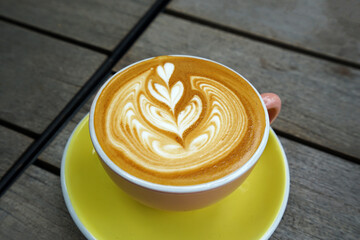 Close up glass cup of hot Latte art coffee on wooden tray table