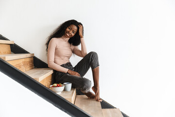 Fototapeta premium Happy young african woman sitting on stairs