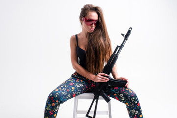 Beautiful strong and independent girl stands with a gun and shows her strength