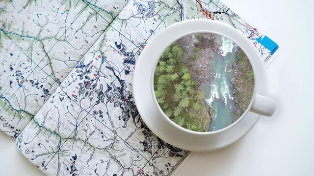 Aerial top view of the mountains and the river. The picture inside the cup standing on the map