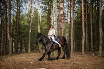 Beautiful girl with her Andalusian horse in the winter forest