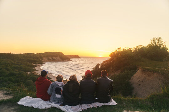 A group of friends watching the sunset at sea. View from the back. High-quality photo - Powered by Adobe