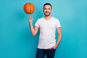 Portrait of his he nice attractive sporty sportive cheerful cheery bearded guy spinning ball playing basketball isolated over bright vivid shine vibrant blue color background