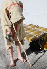 wanderer with a stick and barefoot Asks for alms under a ruined
