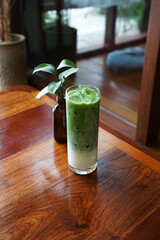 Close up glass of Iced Matcha green tea latte on wooden table