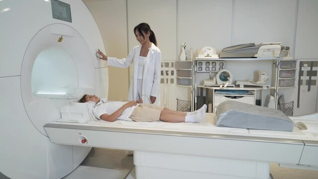 Magnetic resonance imaging, young asian woman doctor performs a magnetic tomographic examination of a boy, MRI, modern technologies in medicine, end of the procedure.