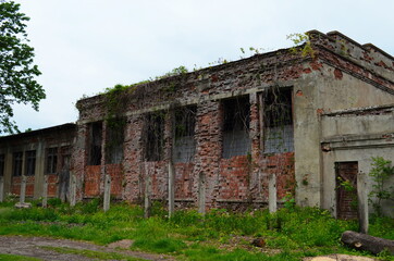 A wall of an old abandoned brick building with broken windows.