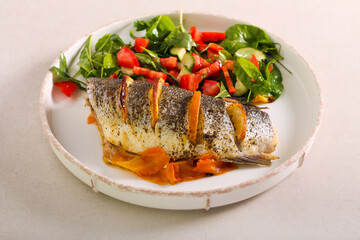 Orange sea bass fish baked on carrot, served with salad