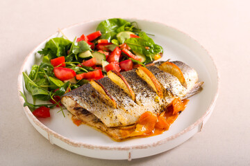 Orange sea bass fish baked on carrot, served with salad
