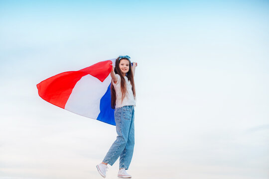 A beautiful brunette girl holds a French flag in her hands. Bastille day