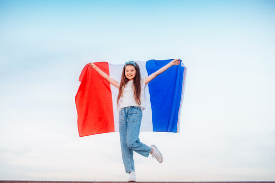 A beautiful brunette girl holds a French flag in her hands. Bastille day