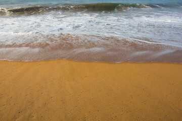 beautiful filled frame close up seascape wallpaper background shot of golden orange sand with white foamy waves of the Indian ocean forming pretty textures and patterns. Pitiwella beach, Sri Lanka