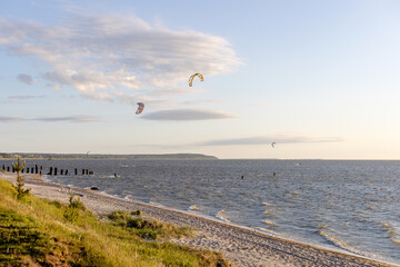 kitesurfers ride the sea on a sunny evening against the backdrop of a beautiful landscape