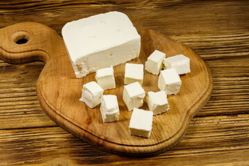 Feta cheese on cutting board on a wooden table