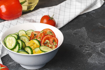 Ceramic bowl of tomato and cucumber salad on table