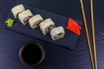 Uramaki sushi rolls with surimi on a black slate. Top view
