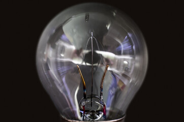 Close up of glass light bulb isolated with tungsten filament on black background