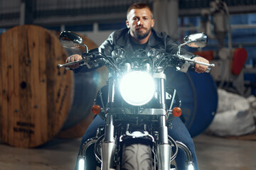 Fototapeta na wymiar Man motorcyclist sitting on his motorbike in underground parking
