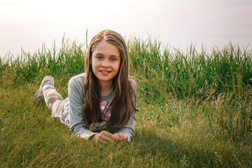 Happy little girl baby lying on the green grass