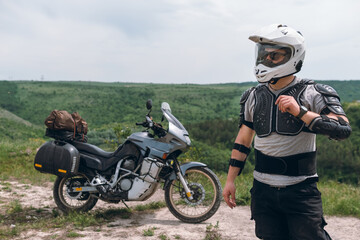 Biker in a helmet and motorcycle equipment, jacket turtle, body armor. Close. In the background a touristic motorcycle. The concept of extreme and hobby. Traveling by bike.