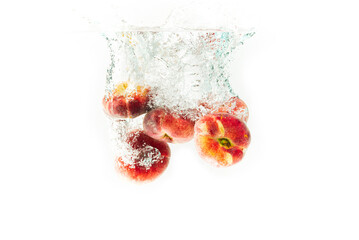 Five chinese flat donut peaches isolated on white splashing into water.