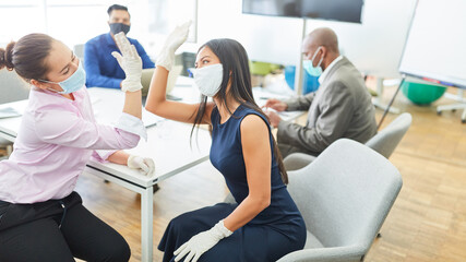 Two business women do the fist bump in the office