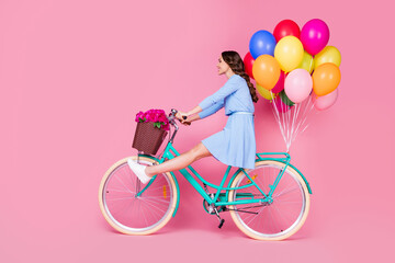 Full length body size profile side view of attractive cheery wavy-haired lady riding bike without legs wearing smart casual delivering decoration having fun isolated pink pastel color background