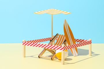 Sunbed with umbrella, surfboard and ball on the beach. Isolated vacation spot at resort. Minimalistic miniature composition. New normal, safe social distance. Copy space.