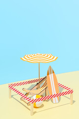 Sunbed with umbrella, surfboard and ball on the beach. Isolated vacation spot at resort. Minimalistic miniature composition. New normal, safe social distance. Copy space.
